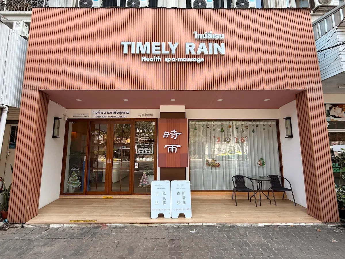时雨 Timely Rain Spa 店面外观,木质格栅立面与中英泰三语招牌,门口立有古法抓龙筋、抓凤筋介绍牌